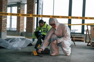 Knive ,and blood is on the ground. Detectives are collecting evidence in a crime scene near dead body photo