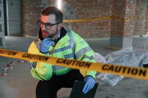 Sitting near caution police tape. Detectives are collecting evidence in a crime scene with dead body photo