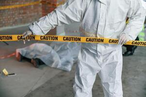 Holding caution police tape. Detectives are collecting evidence in a crime scene near dead body photo