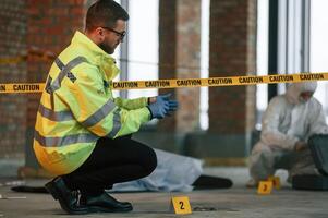 Dead body, is on the ground. Detectives are collecting evidence in a crime scene photo