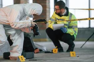 Woman is using, camera, making photos. Detectives are collecting evidence in a crime scene near dead body photo