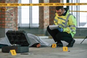 Notepad with information. Male, detective is collecting evidence in a crime scene near dead body on the construction site photo