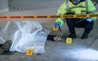 Knife ,is on the floor. Male detective is collecting evidence in a crime scene near dead body on the construction site photo