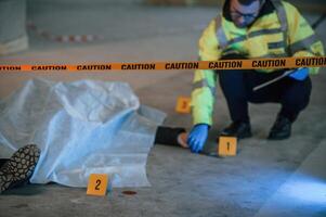 Knife is on the floor. Male detective is collecting evidence in a crime scene near dead body on the construction site photo