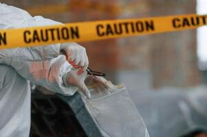 Bullet sleeve in hand. Detective are collecting evidence in a crime scene photo