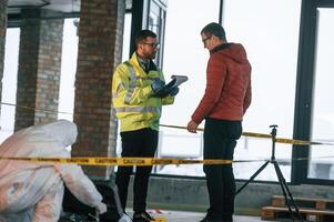 The ,witness is being questioned. Two detectives are collecting evidence in a crime scene photo