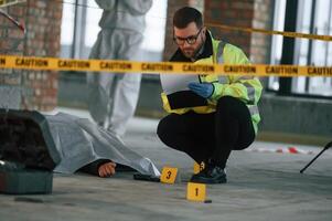 Dead, body, is on the ground. Detectives are collecting evidence in a crime scene photo