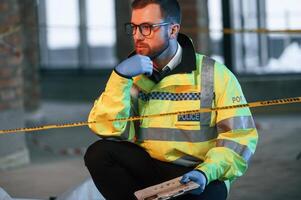 Sitting and thinking. Male detective is collecting ,evidence in a crime scene on the construction site photo