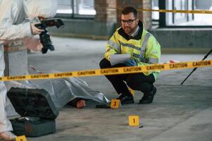 Woman is making ,photos by camera. Detectives are collecting evidence in a crime scene near dead body photo