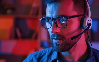 Portrait ,of man that is sitting by a computer indoors at home. Neon lighting photo
