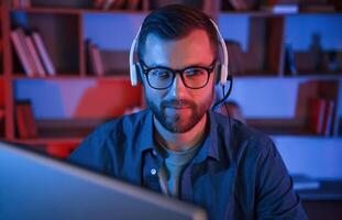 Read, and blue neon lighting. Man is sitting by a computer indoors at home photo