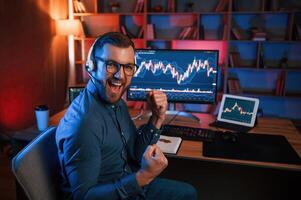 Happy, stock trader is working, by pc indoors and celebrating success. Conception of exchange and money photo