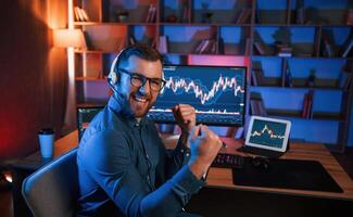 Happy, stock,, trader is working by pc indoors and celebrating success. Conception of exchange and money photo