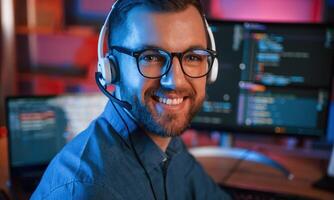 Positive professional programme,r is working indoors and smiling. Neon lighting photo