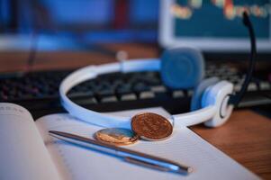 Close up view of physical bitcoins, headphones, notepad and pen that is on the table photo