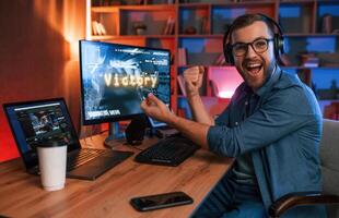 Uplifting and energized man, is playing the shooter game on his computer. Neon lighting photo