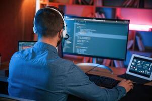 Professional programmer is working indoors.. Neon lighting photo