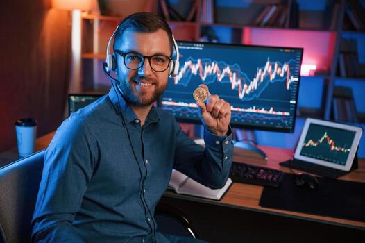 Holding bitcoin.. Stock, trader is working by pc indoors. Conception of exchange and money photo