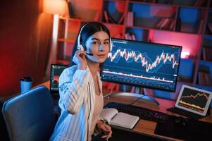 Looking,into ,the camera. Female stock trader is working by pc indoors. Conception of exchange and money photo
