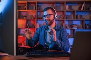 Read and blue neon lighting. Man is sitting by a computer indoors at home photo