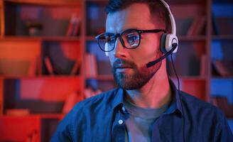 Portrait, of man that is sitting by a computer indoors at home. Neon lighting photo
