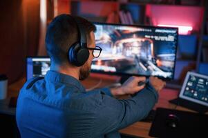 Concentrated man ,is playing the ,shooter game on his computer. Neon lighting photo