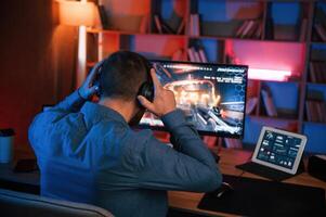 Man is playing the ,shooter game on his computer. Neon lighting photo