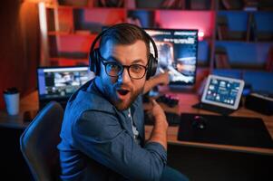 Man is playing, the shooter, game on his computer. Neon lighting photo