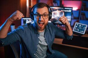 Uplifting and energized man is playing the shoote,r game on his computer. Neon lighting photo