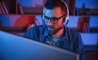 Read ,and blue neon lighting. Man is sitting by a computer indoors at home photo