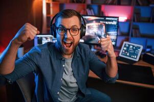 Uplifting and energized, man is playing the shooter game on his computer. Neon lighting photo
