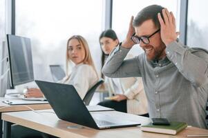 Man, is feeling mbad about failure. Team are working together in the office. Conception of business photo