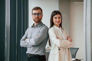 Man ,with woman is standing and posing. Successful team are working together in the office. Conception of business photo