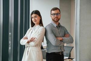 Man with woman is, standing and posing. Successful team are working together in the office. Conception of business photo