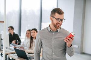 Man is holding a can with drink. Successful team are working together in the office. Conception of business photo
