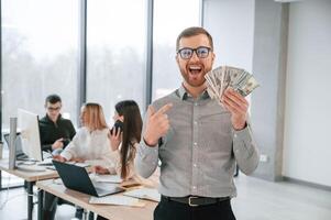 Man, ism holding money in hands. Successful team are working together in the office. Conception of business photo