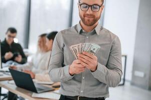 Man, is holding money in ,hands. Successful team are working together in the office. Conception of business photo