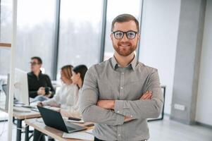 Man is standing with arms crossed. Successful team are working together in the office. Conception of business photo