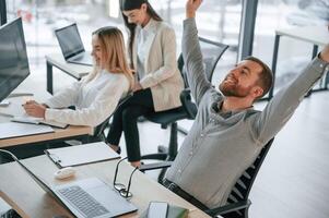 Man is satisfied, about results.. Successful team are working together in the office. Conception of business photo