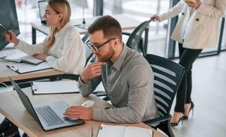 Side view of man that is sitting. Successful team are working together in the office. Conception of business photo
