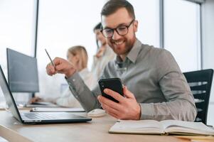 Smiling, and holding smartphone. Successful ,team are working together in the office. Conception of business photo