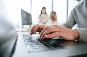 Close up view, using laptop. Successful team are working together in the office. Conception of business photo