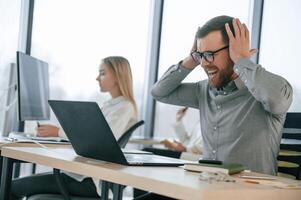 Man is, feeling bad about failure. Team are working together in the office. Conception of business photo