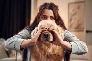 Covering, face with hands. Love gesture. Woman is with golden retriever dog at home photo