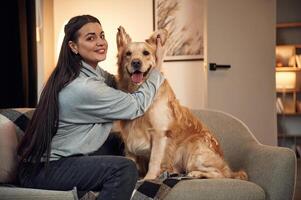 Playing and ,sitting on the sofa. Woman is with golden retriever dog at home photo