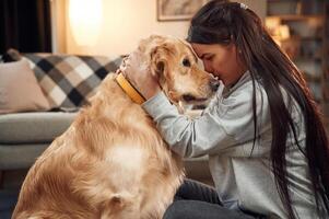 Side view.. Having fun, embracing.. Woman is with golden retriever dog at home photo