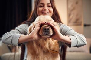 Covering face with hands. Love gesture. Woman is with golden retriever dog at home photo