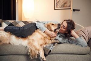 Lying,, down on the sofa together. Woman is with golden retriever dog at home photo