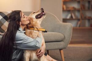 Kissing the dog. Woman is with golden retriever at home photo