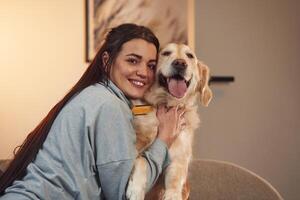 Happy owner of beautiful animal. Woman is with, golden retriever dog at home photo